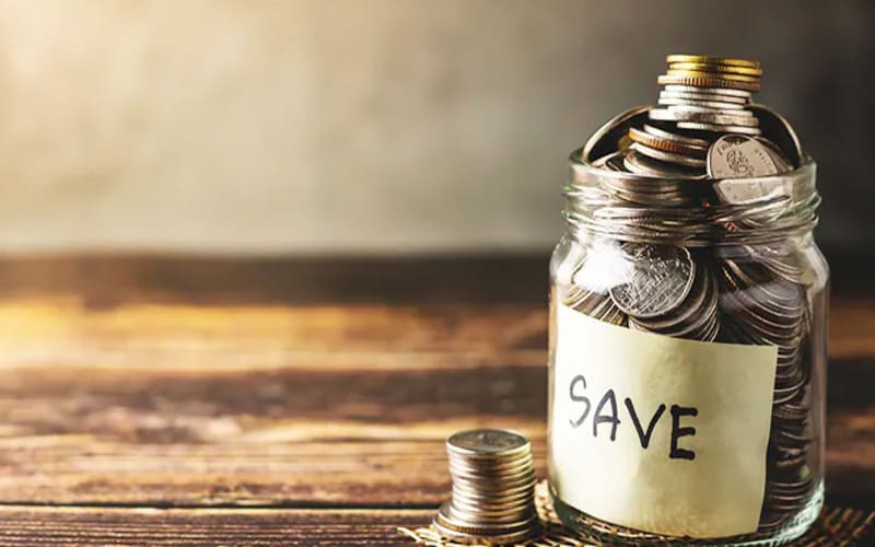 Hũ thủy tinh đựng đầy tiền xu, tượng trưng cho việc tiết kiệm hợp lí